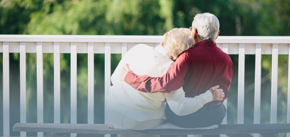 retired senior white couple sitting porch assisted living facility hugging
