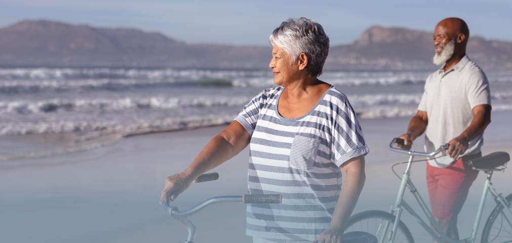 Retired couple independent living on beach bicycles african american
