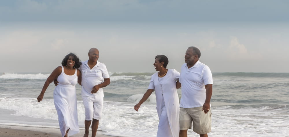 2 retired senior independent living black couples on beach