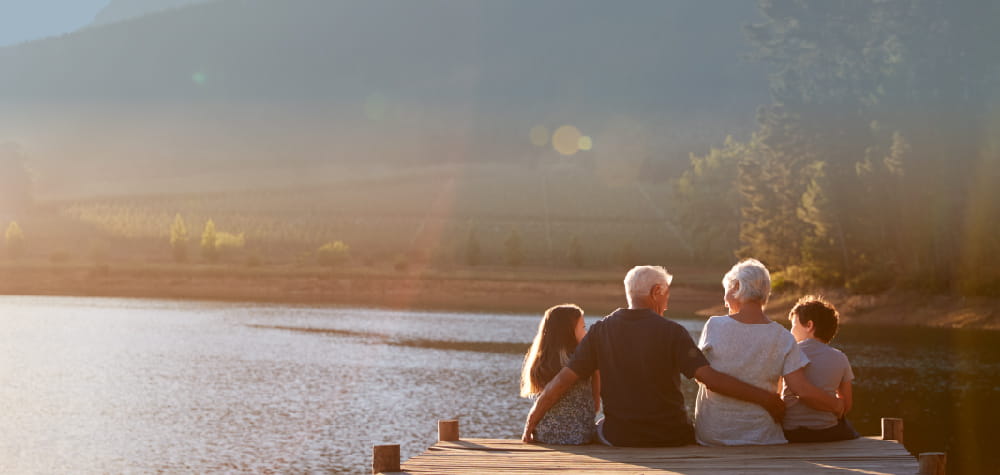 Retired elder white grandparents special needs planning grandkids on lake dock 